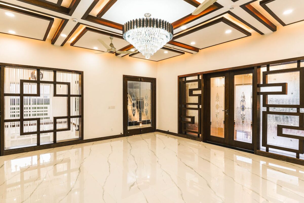 Luxurious interior with a stunning chandelier, intricate woodwork, and polished marble flooring.
