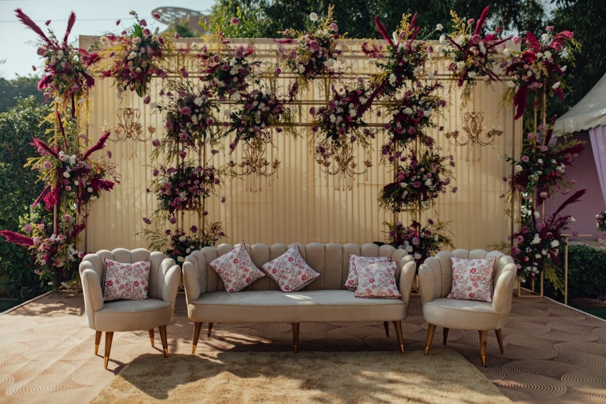 Beautifully decorated outdoor wedding seating with floral arrangements and chandeliers.